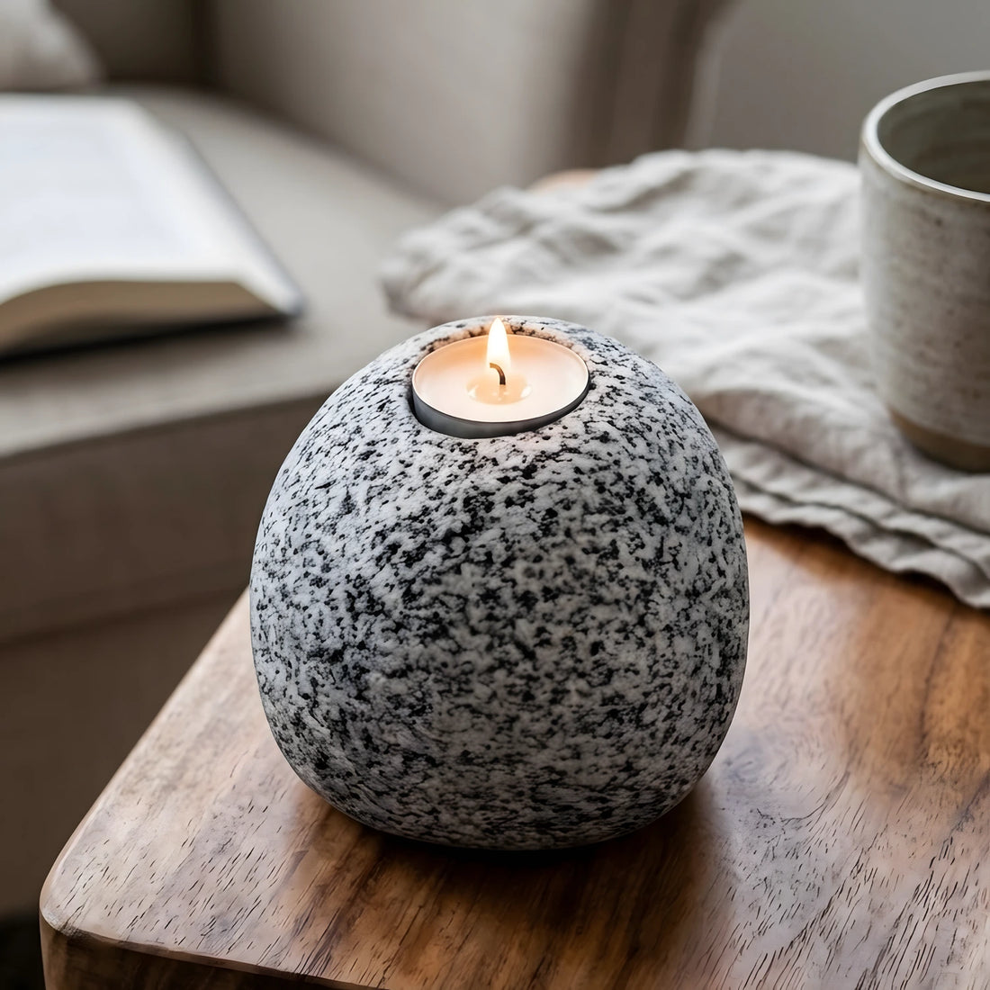 Ahşap masa üzerinde dekoratif Bergama graniti doğal taş tealight mumluk, arka planda kitap ve kupa.