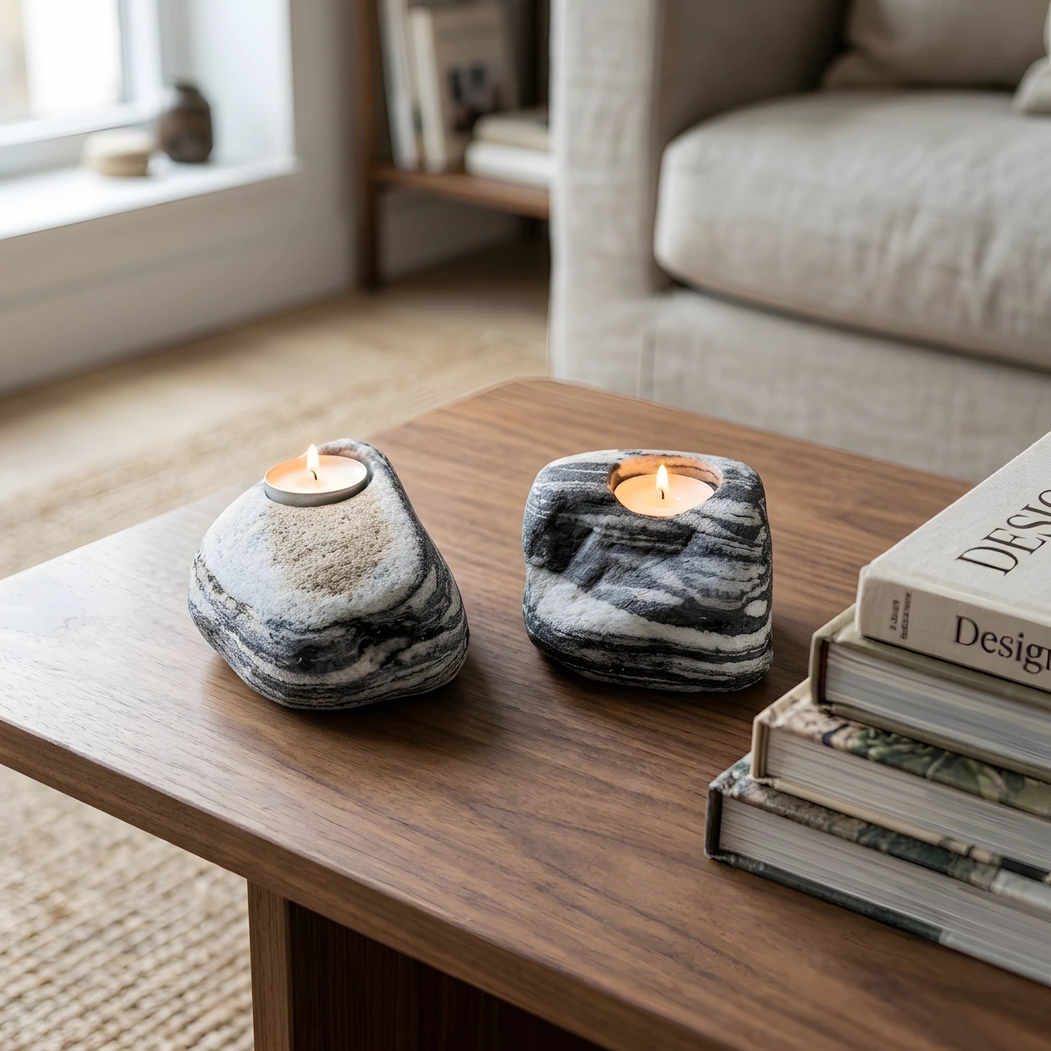 Ahşap sehpa üzerinde kitapların yanında duran iki adet yanan doğal taş tealight mumluk, oturma odası ambiyansı.